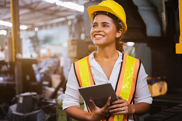 Smiling maintenance technician working with maintenance management software on a tablet